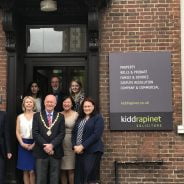 Group of people with Mayor standing outside an office.