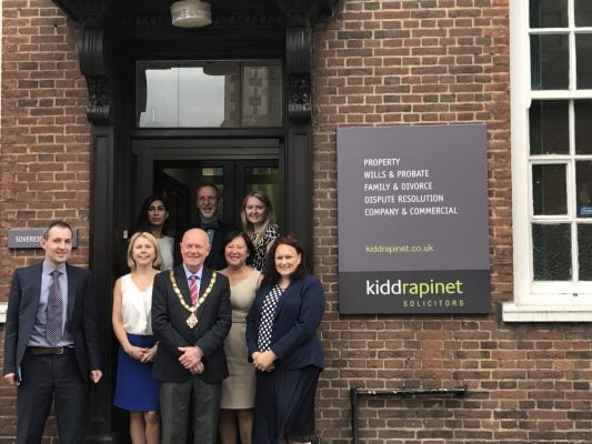 Group of people with Mayor standing outside an office.