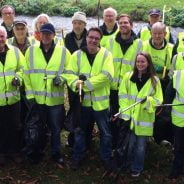 Group of litter pickers in high viz jackets and holding bags and litter picks