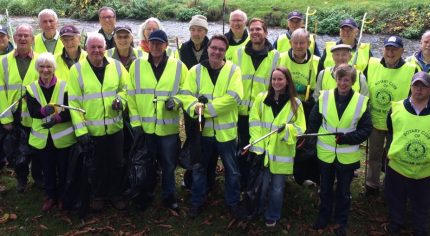 Group of litter pickers in high viz jackets and holding bags and litter picks