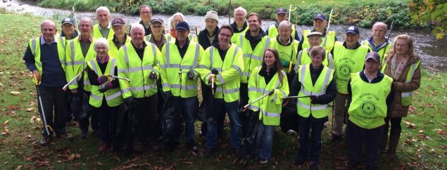 Group of litter pickers in high viz jackets and holding bags and litter picks