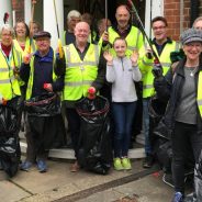 Group of people in high visibility jackets holding litter pickers and black sacks