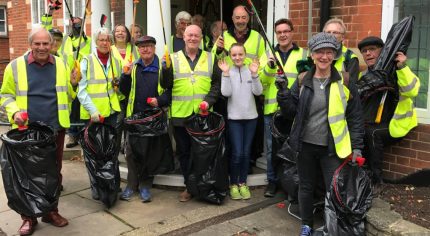 Group of people in high visibility jackets holding litter pickers and black sacks