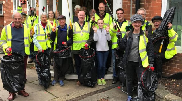 Group of people in high visibility jackets holding litter pickers and black sacks