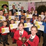 Group of children holding certificates and a trophy.