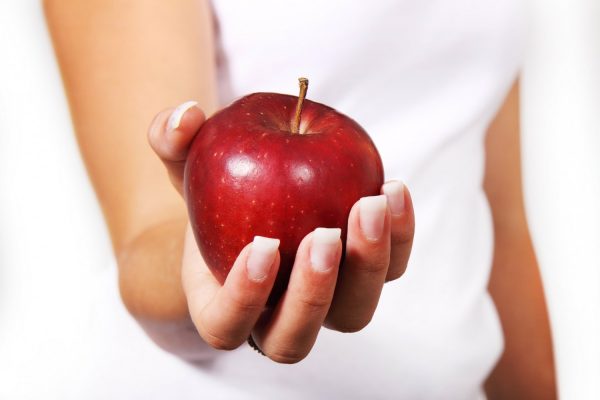 Female hand holding a shiny red apple.
