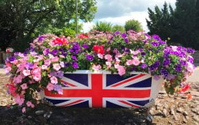 Bath tub filled with flowers and a union flag on side of bath.