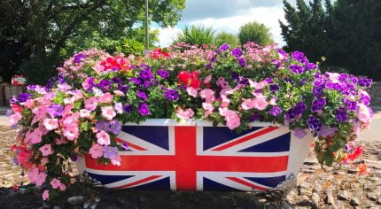 Bath tub filled with flowers and a union flag on side of bath.