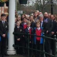 Group of students and adults outside a red brick building.