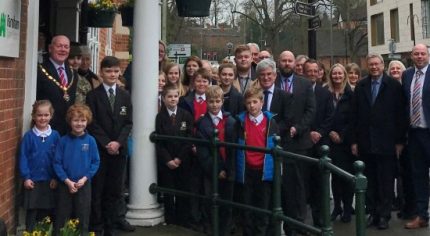 Group of students and adults outside a red brick building.