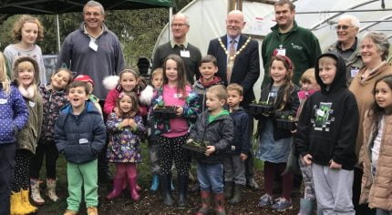 Group of children and adults outside a poly tunnel.