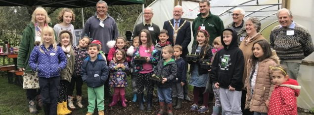 Group of children and adults outside a poly tunnel.