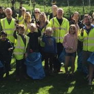 People in high viz jackets holding blue sacks and litter pickers.