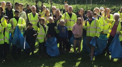 People in high viz jackets holding blue sacks and litter pickers.