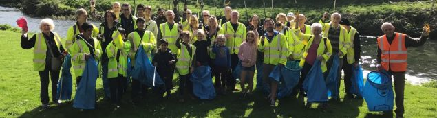 People in high viz jackets holding blue sacks and litter pickers.