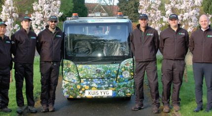 Group eight males standing next to a vehicle with flowery livery.