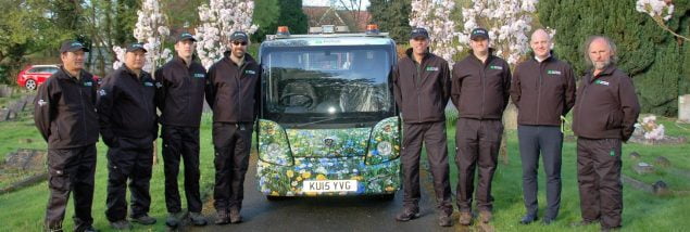 Group eight males standing next to a vehicle with flowery livery.
