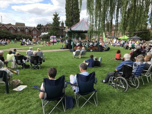 People in park facing a bandstand.