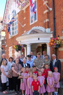 Group of children with soldiers and adults.