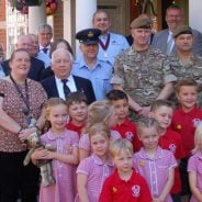 Group of children with soldiers and adults.