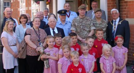 Group of children with soldiers and adults.