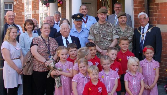 Group of children with soldiers and adults.