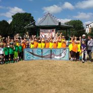 Large group children standing behind a painting of an otter.