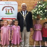 School children and the Mayor stand next to a large hanging basket.
