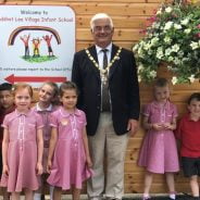 School children and the Mayor stand next to a large hanging basket.