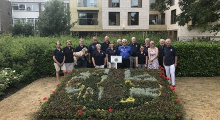 Group of people standing behind a carpet bed