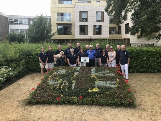 Group of people standing behind a carpet bed