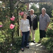 Female, Mayor and male stand under an archway in a pretty garden.