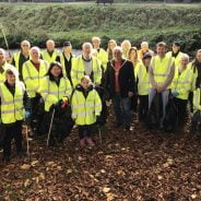 People in high viz jackets holding black sacks and litter pickers.