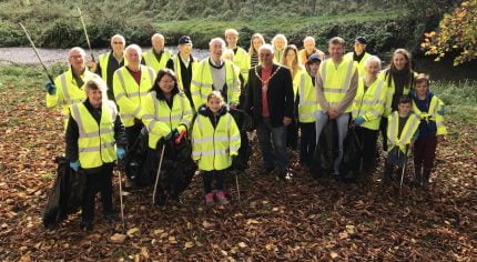 People in high viz jackets holding black sacks and litter pickers.