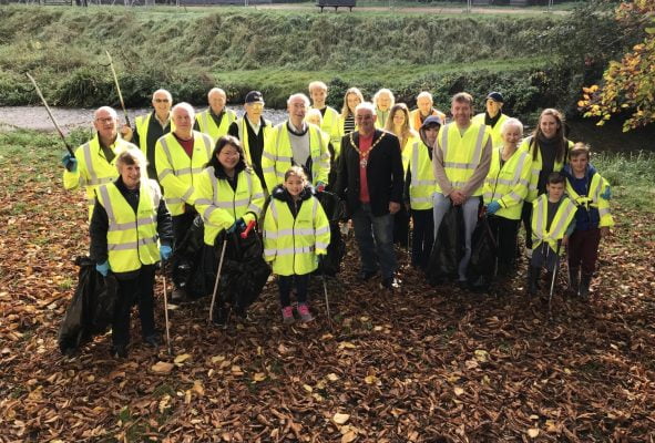 People in high viz jackets holding black sacks and litter pickers.