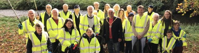 People in high viz jackets holding black sacks and litter pickers.