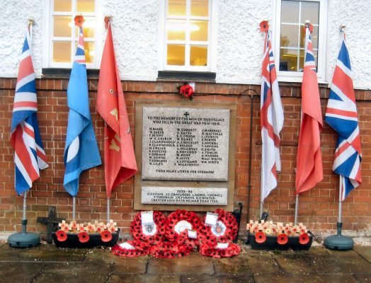 War memorial with flags and poppies around