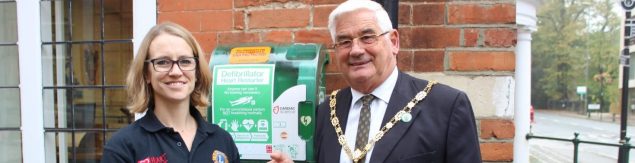 Female and Mayor in front of green defibrillator box