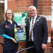 Female and Mayor holding a defibrillator in a box