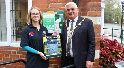 Female and Mayor holding a defibrillator in a box