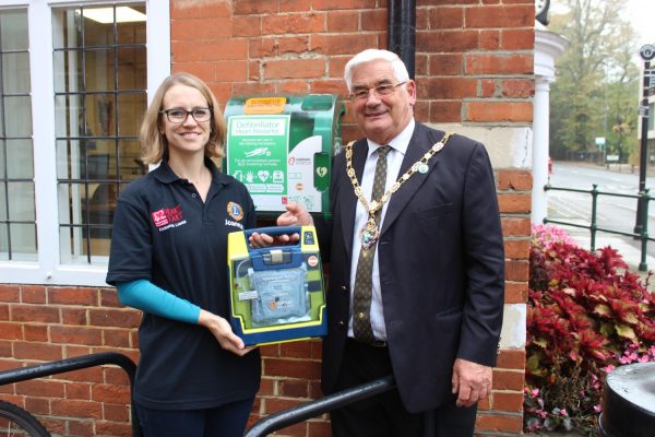 Female and Mayor holding a defibrillator in a box