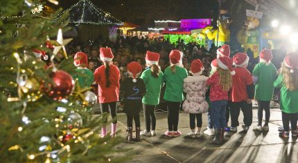 Back of children on stage. Christmas tree.