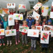 Children holding paintings of leaves.