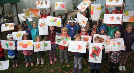 Children holding paintings of leaves.