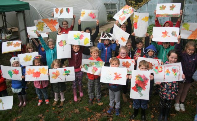 Children holding paintings of leaves.
