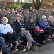 Older people in wheelchairs and soldiers standing behind.