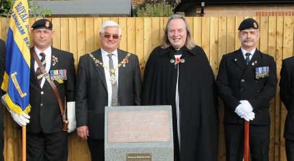 Mayor, men in uniform and vicar at a war memorial.