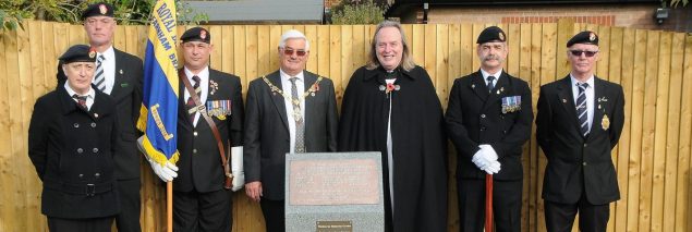 Mayor, men in uniform and vicar at a war memorial.