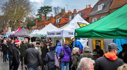 Crowd of people at an outdoor market. Colourful gazebos in street