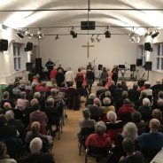 Older people watching a band perform inside a church hall